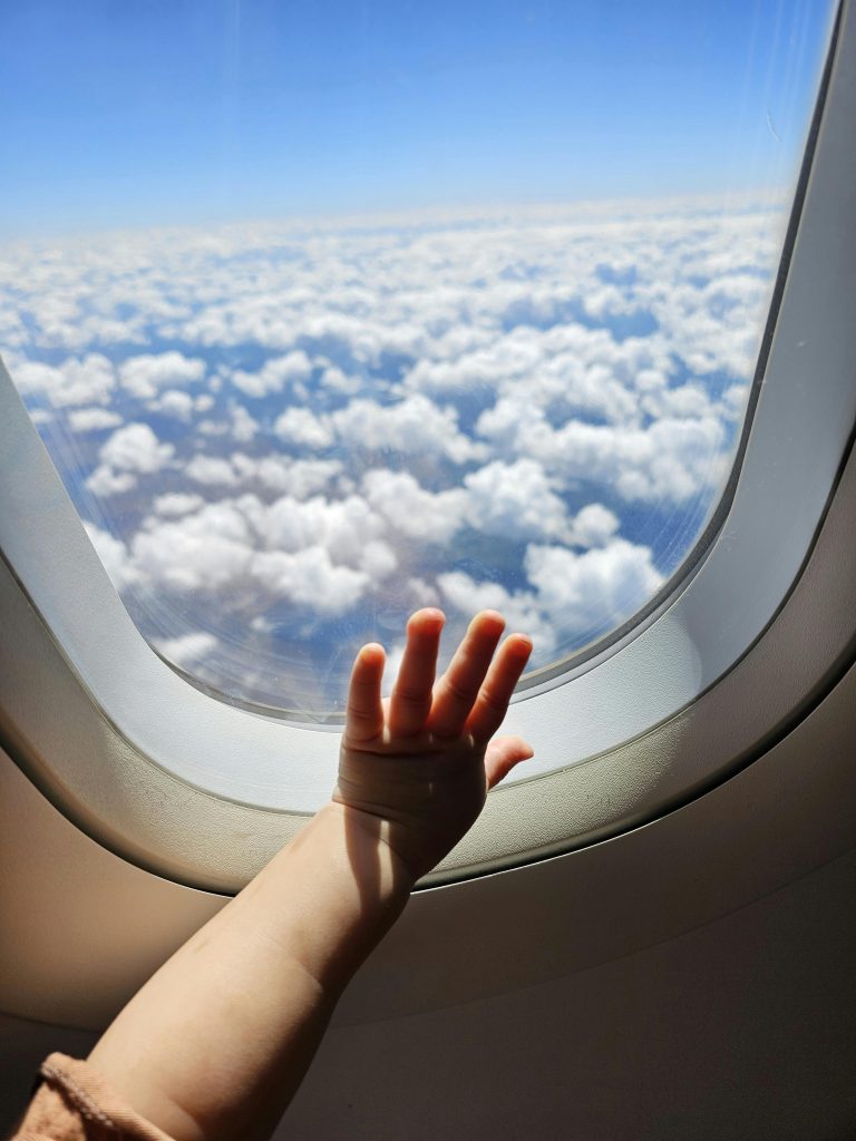 Photo représentant la main d'un enfant sur le hublot intérieur d'un avion.